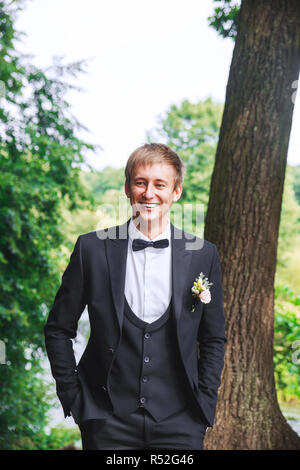 groom at wedding tuxedo smiling and waiting for bride. Rich groom at wedding day. Elegant groom in costume and bow-tie. Stock Photo