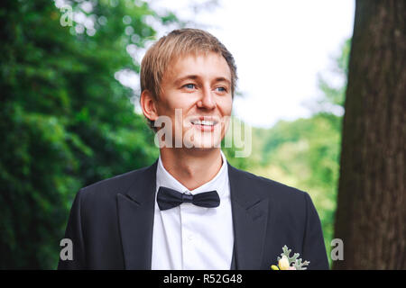 groom at wedding tuxedo smiling and waiting for bride. Rich groom at wedding day. Elegant groom in costume and bow-tie. Stock Photo