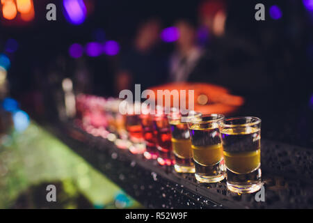 Variation of hard alcoholic shots served on bar counter. Blur bottles on background. Stock Photo