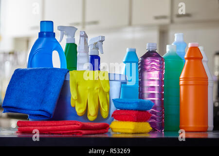Household cleaning items in basket on kitchen table with blurred background Stock Photo