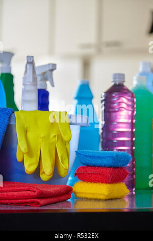 Household cleaning items in basket on kitchen table with blurred background Stock Photo