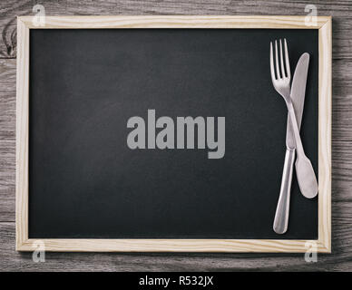 Empty menu blackboard with knife and fork on wooden background. Food background Stock Photo