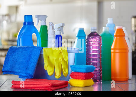 Household cleaning items in basket on kitchen table with blurred background Stock Photo