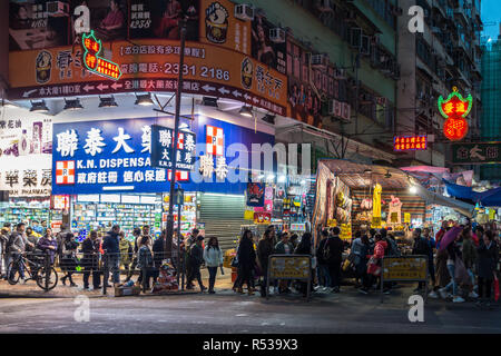 Nathan Road in Mong Kok area at late afternoon, full of people, street vendors and neon-lighted shops. Hong Kong, Kowloon, January 2018 Stock Photo