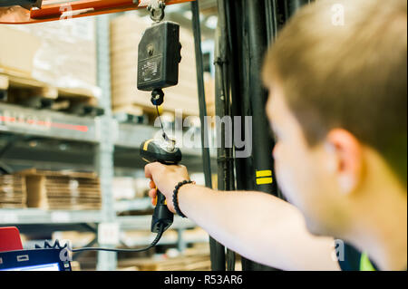 young man in working clothes, driver Reachtruck busy working on the logistics warehouse store Stock Photo