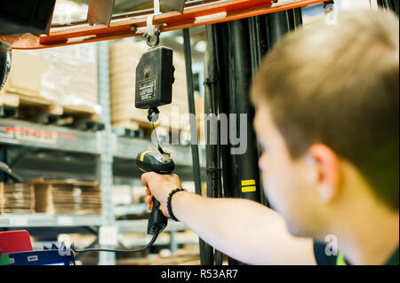 young man in working clothes, driver Reachtruck busy working on the logistics warehouse store Stock Photo