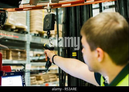 young man in working clothes, driver Reachtruck busy working on the logistics warehouse store Stock Photo