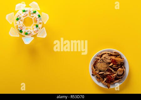 top view studio shoot Chinese herb medicine and pills on yellow background with copy space Stock Photo