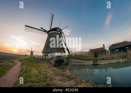 Windmill and bridge along a canal in Holland, a beautiful scene at sunset. photographed near the river Rotte, close to the city of Rotterdam, Holland. Stock Photo