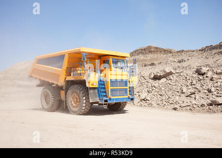 Yellow dump truck moving in a coal mine Stock Photo