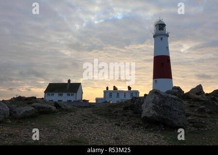 Lighthouse on early summer morning in Isle of Portland in England. Rocky coast near the sea. Some lovely clouds on the blue sky. Stock Photo