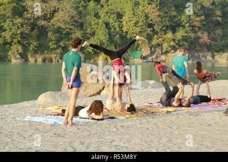 International students performing acro yoga at Ganga Beach, Rishikesh, India Stock Photo