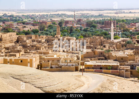 Oasis and ruins of ancient middle eastern Arab town built of mud bricks, old mosque with minaret. Al Qasr, Dakhla Oasis, Western Desert, Sahara, Egypt Stock Photo