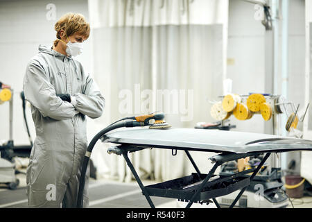 mechanic grinds car part for painting. Car body work auto repair paint after accident Stock Photo