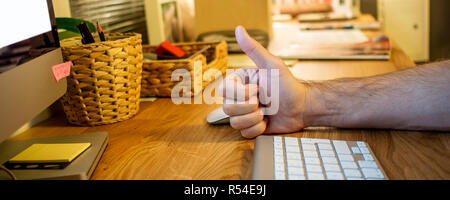 close-up of a man sitting at the desk and typing on the keyboard of his desktop computer in the evening in the home office Stock Photo