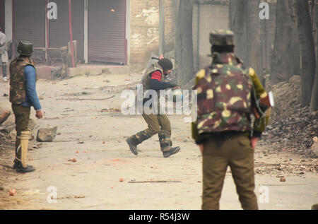 Indian Government policeman dodging a stone thrown by a Kashmiri protester during clashes between people and forces in Kuthipora area of Chattergam, District Budgam, Indian Administered Kashmir on 28 November 2018. Top Lashkar-e-Toiba (LeT) commander Naveed Jatt was killed along with his associate in a gunfight with the Indian government forces in Chattergam area. Naveed Jatt alais Hanzallah was a resident of Pakistan and was affiliated with LeT, Police said. Three residential houses were damaged in the gunfight. Many locals including three Indian Army personnel were injured in the encounter Stock Photo