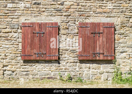 Closed wooden shutters on the  exterior of a stone barn, Derbyshire, England, UK Stock Photo
