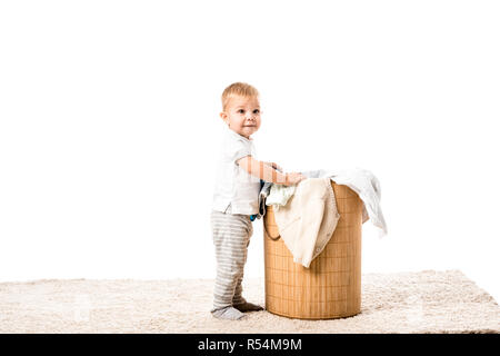 toddler boy standing in front of wicker laundry basket and smiling isolated on white Stock Photo