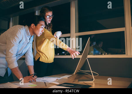 businessman and woman discussing business work late in office. Woman entrepreneur explaining work to her business colleague. Stock Photo