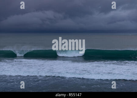 Storm clouds rolling in over the ocean and so are some perfect waves Stock Photo