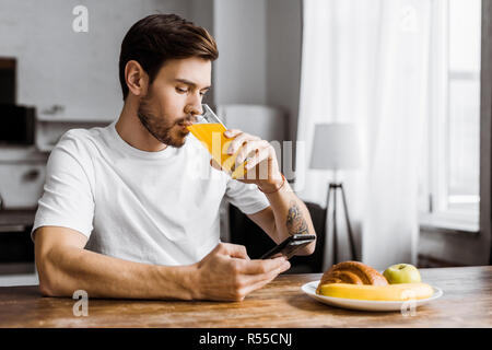attractive young man using smartphone during breakfast at home Stock Photo
