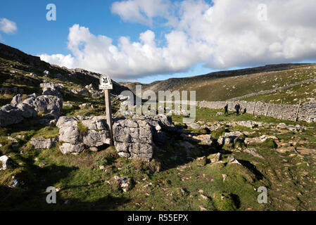 Walkers in the limestone rock valley above Malham Cove, Yorkshire, Dales National Park, UK. Stock Photo