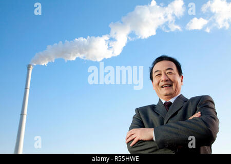 Businessman in Front of Smokestack Stock Photo