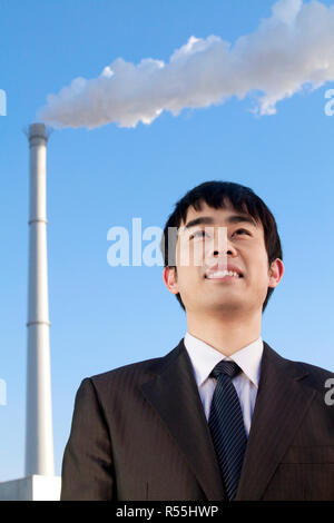 Businessman in Front of Smokestack Stock Photo
