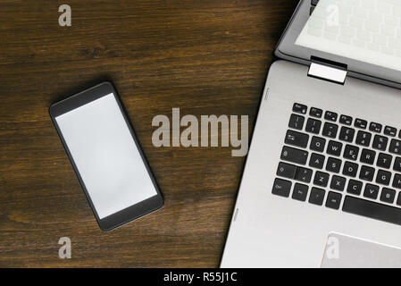 Top view of laptop and smartphone on brown wooden desk, workspace concept Stock Photo