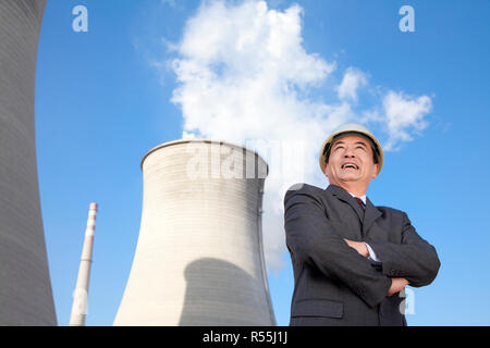 Businessman in front of cooling tower Stock Photo