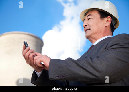 Businessman texting at power plant Stock Photo