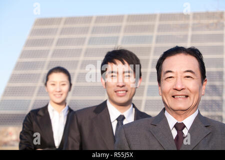 Three Businesspeople in front of Solar Panel Stock Photo