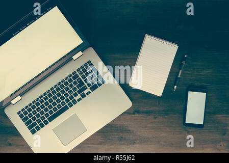 Top view of laptop smartphone and notepad on desk, on vintage wooden workspace Stock Photo