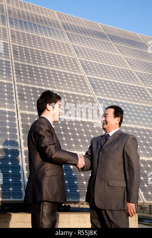 Shaking hands in front of solar panels Stock Photo