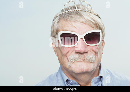 Senior man wearing a tiara and sunglasses Stock Photo