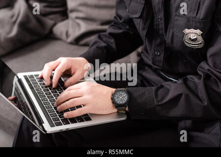 cropped view of policeman typing on laptop keyboard Stock Photo