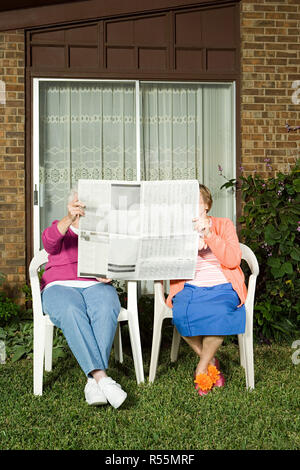 Two senior women sharing a newspaper Stock Photo