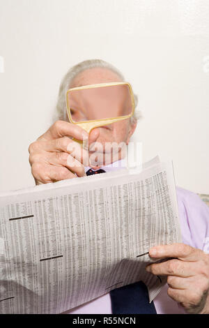 Man reading newspaper with magnifying glass Stock Photo