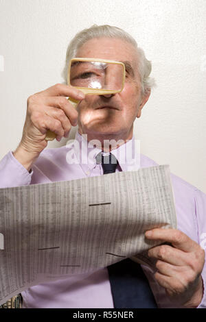Man reading newspaper with magnifying glass Stock Photo
