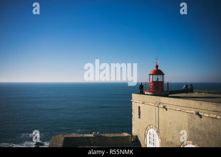 The lighthouse overlooking Praia do Norte beach, in Nazare, Portugal on a calm day. Stock Photo