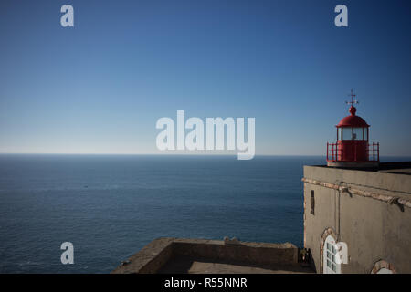 The lighthouse overlooking Praia do Norte beach, in Nazare, Portugal on a calm day. Stock Photo