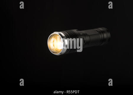 Tactical flashlight, hand on black background, studio light Stock Photo
