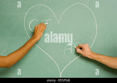 Two students drawing on a blackboard Stock Photo