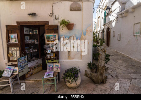 Beautiful small souvenirs shops selling paintings and postcards. Locorotondo, Apulia, Italy, August 2017 Stock Photo