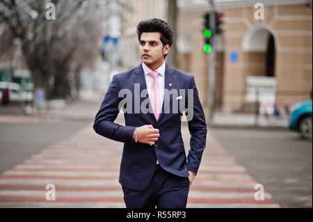 Elegant indian macho man model on suit and pink tie walking at cross pedestrian. Stock Photo