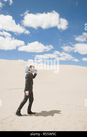 Businessman in desert with bottle Stock Photo