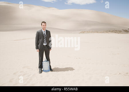 Man in desert with water bottle Stock Photo