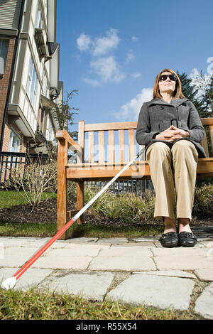 Blind woman sitting on a bench Stock Photo