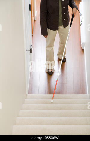 Blind woman using a walking stick on stairway Stock Photo