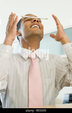 Office worker balancing a pencil on his nose Stock Photo